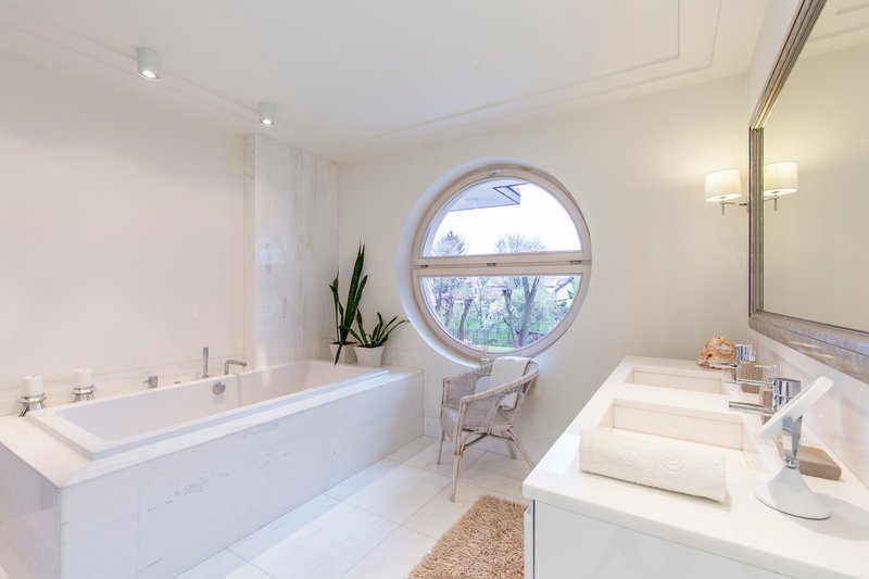 Moderno baño en tonos blancos con bañera en Puebla
